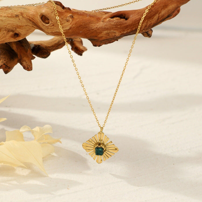 Collier doré avec pendentif losange et perle verte au centre